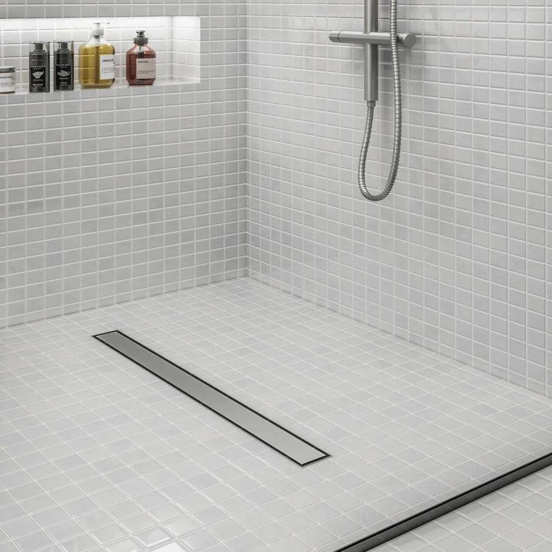 Bay 2-in-1 Linear Drain by QM Drain installed with polished stainless steel grate. Featured in a modern shower setting, highlighting its sleek finish and efficient water drainage.