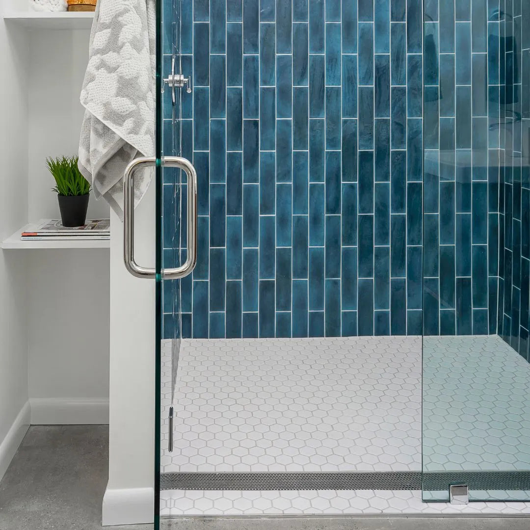 Front view of Perforated Adjustable Delmar Linear Drain installed in a commercial space with white oak wood flooring. Featuring a stainless-steel channel with perforated grate, adjustable frame, and integrated flange for efficient drainage and seamless integration into the floor design.