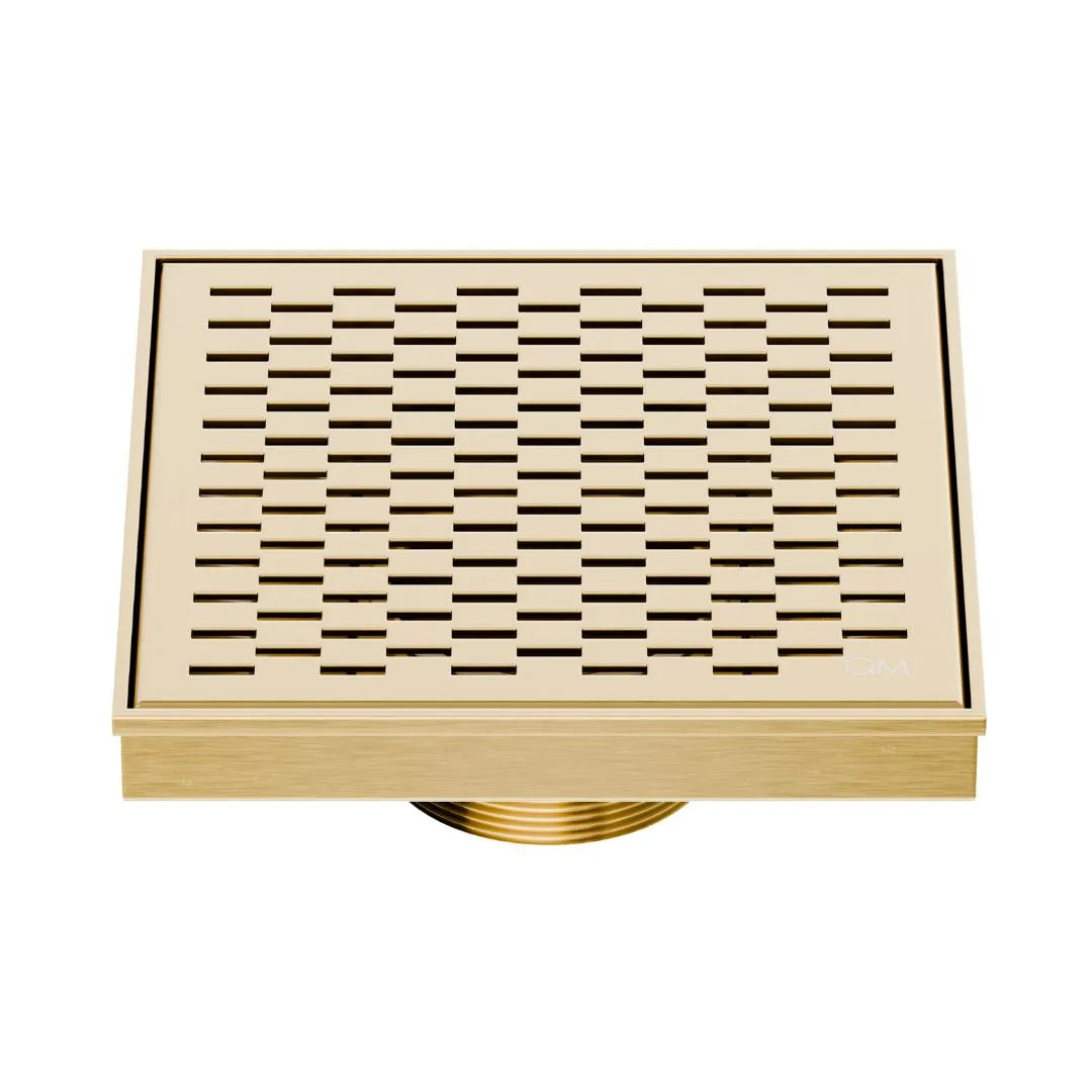 QM Drain Delmar Delta Square Drain 5 3/4-inch in Gold finish, featuring a sleek stainless-steel square-pattern grate. This drain ensures efficient water drainage, seamless tile integration, and a luxurious aesthetic, perfect for high-end shower and bathroom floor installations.