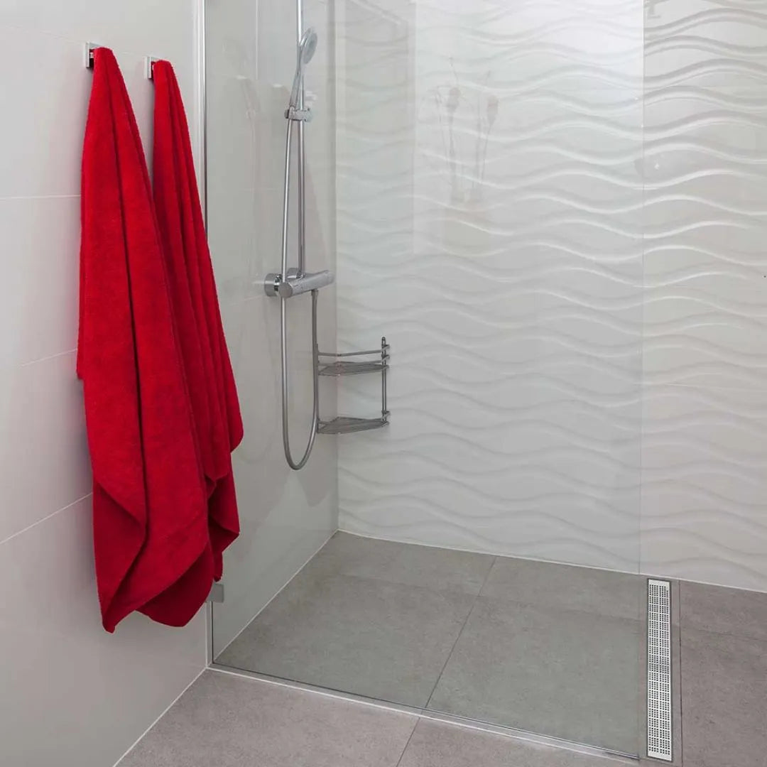 Modern spa-style bathroom scene featuring the QM Drain Kai Linear Drain—sleek stainless-steel channel set into large-format porcelain tiles, with integrated waterproof flange beneath the tile edges, minimalist grate design, and rapid high-flow drainage for a seamless luxury shower aesthetic.