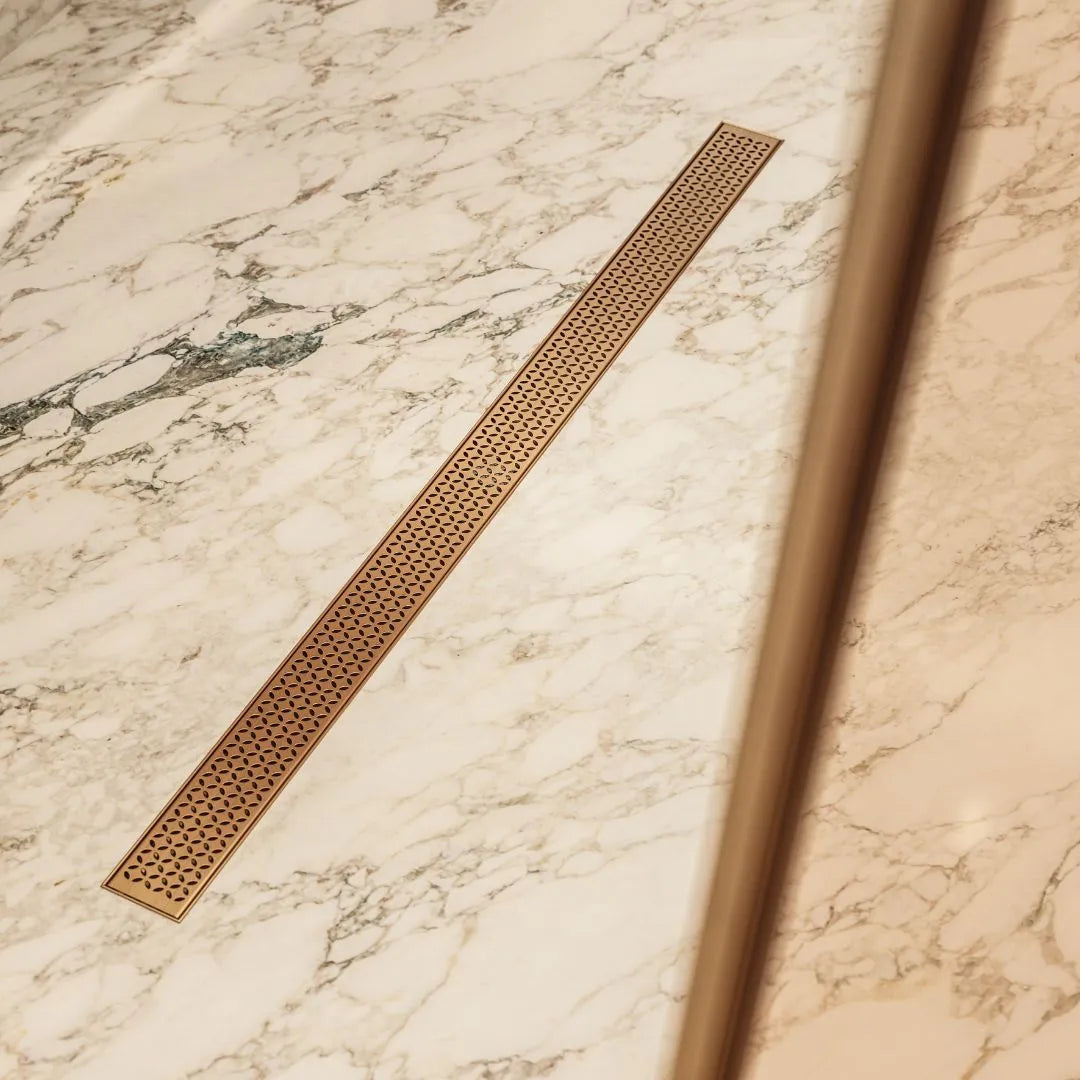 QM Drain Lotus Linear Drain, featuring a sleek stainless-steel channel with a perforated grate design. The drain ensures efficient water drainage and seamless integration into modern shower floors, elevating the minimalist aesthetic and luxury of contemporary bathroom designs.