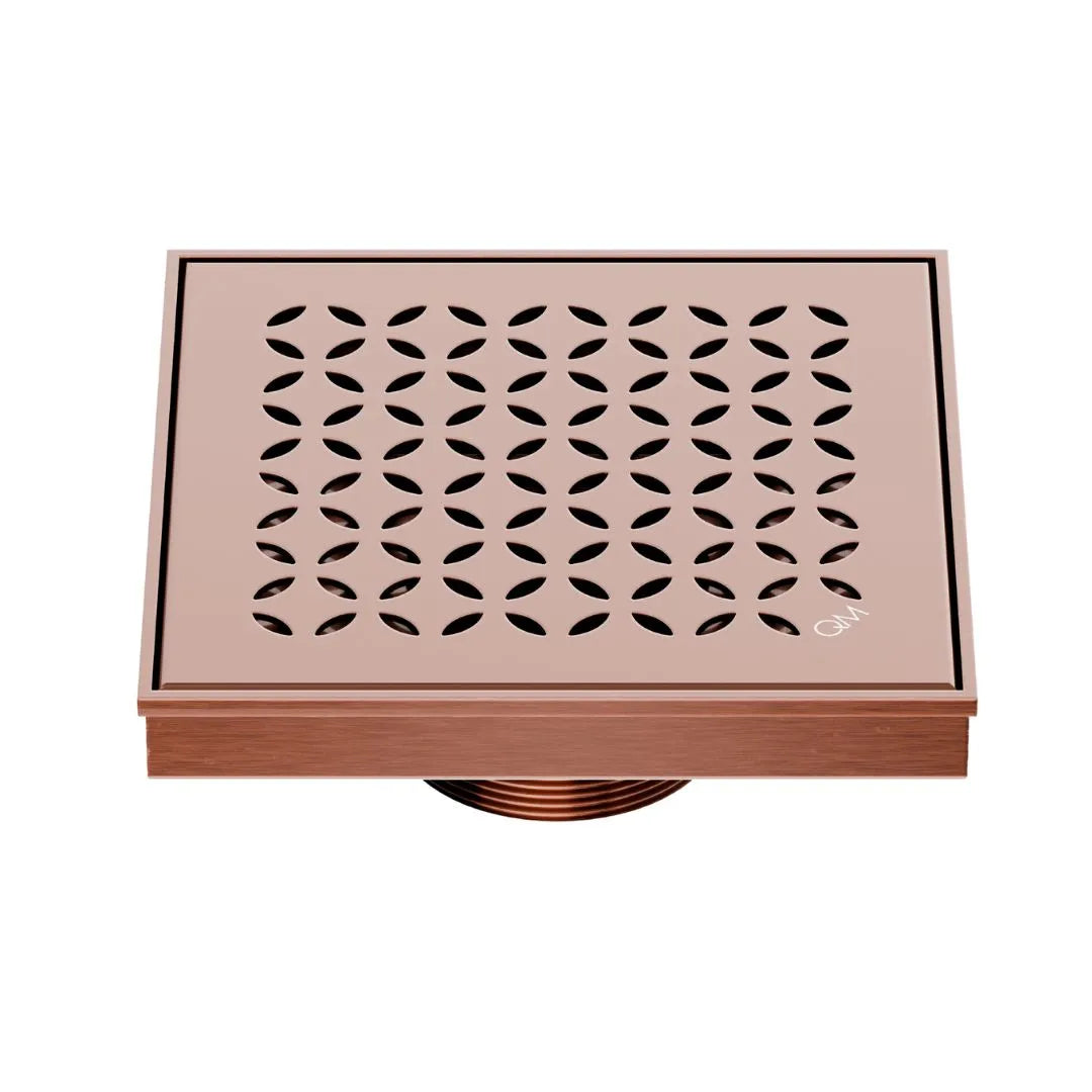 QM Drain Delmar Lotus Square Drain 5 3/4-inch in Bronze finish, featuring a sleek stainless-steel channel with an elegant floral-pattern grate. This drain offers efficient water drainage, seamless tile integration, and an elegant aesthetic, ideal for luxury shower and bathroom floor installations.