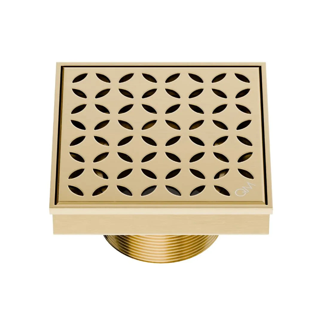 QM Drain Delmar Lotus Square Drain 4x4-inch in Gold finish, featuring a sleek stainless-steel channel with an elegant floral-pattern grate. This drain ensures efficient water drainage, seamless tile integration, and a luxurious aesthetic, perfect for high-end shower and bathroom floor installations.