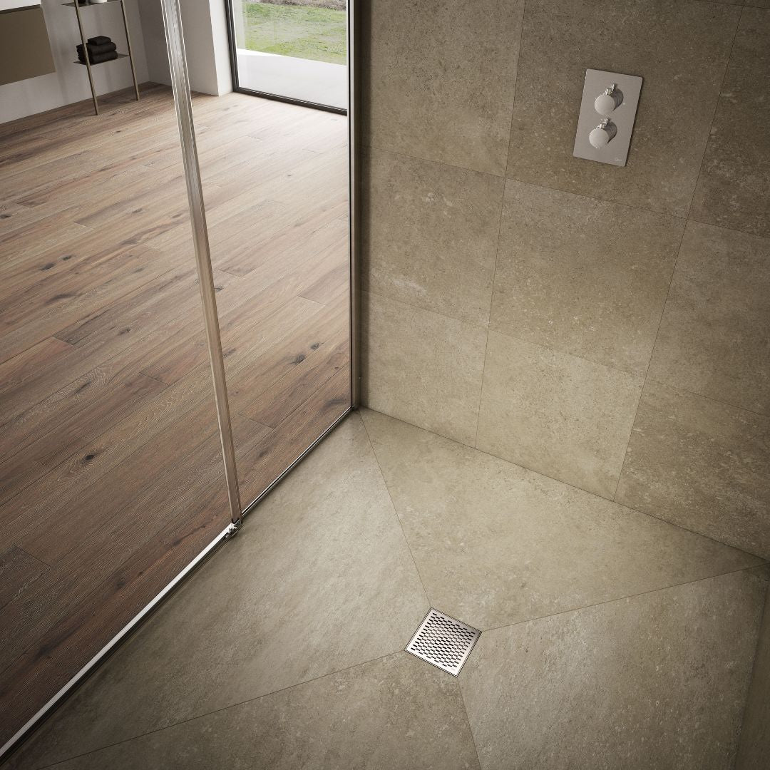 QM Drain Delmar Delta Square Drain installed in a modern bathroom, featuring a sleek stainless-steel square-pattern grate. This image highlights seamless tile integration and efficient water drainage, offering a contemporary and minimalist aesthetic for luxury shower and bathroom floor installations.
