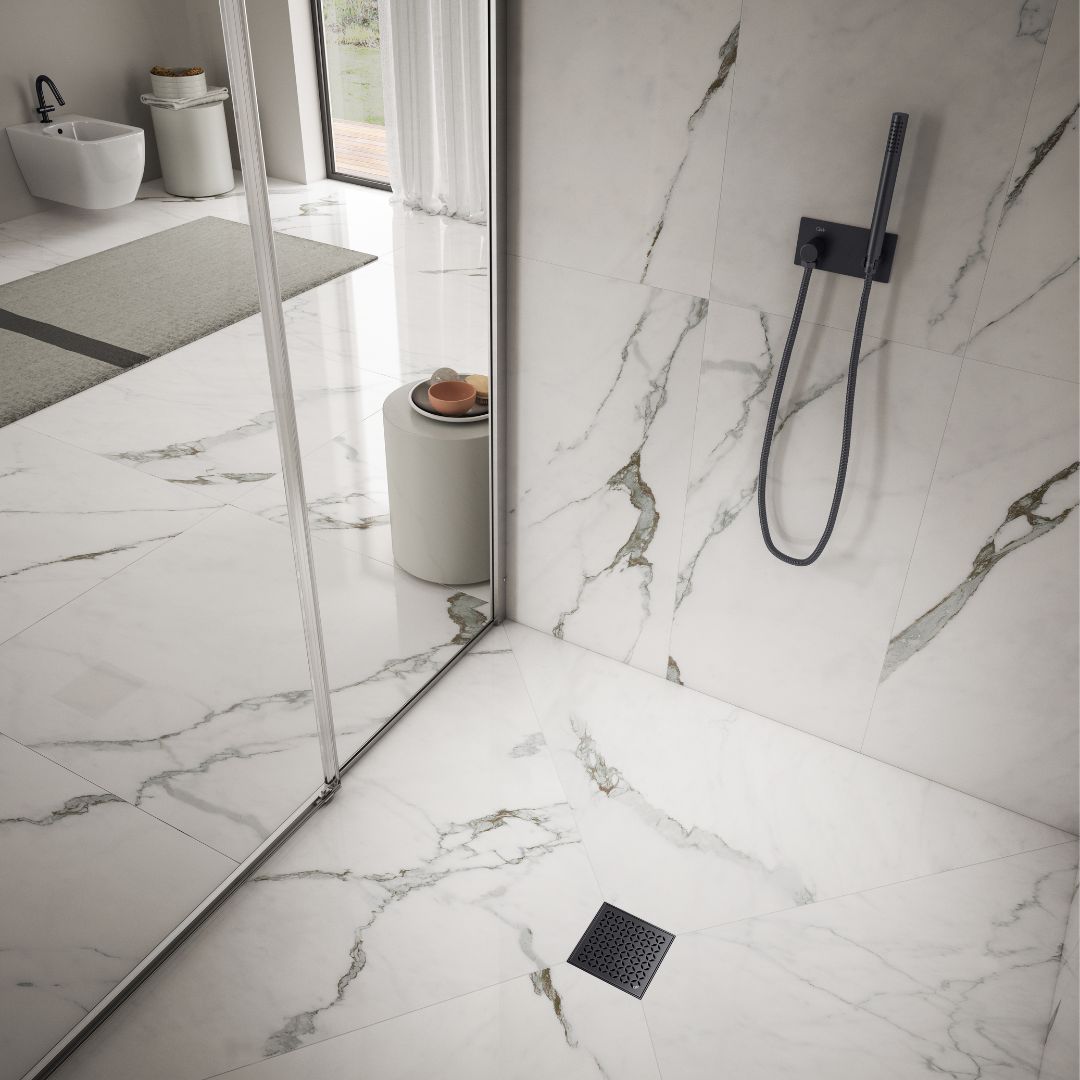 QM Drain Delmar Lotus Square Drain installed in modern showers, available in 4-inch and 5 3/4-inch sizes. Featuring a sleek stainless-steel floral-pattern grate, these drains offer efficient water drainage and seamless tile integration for luxury bathroom installations.