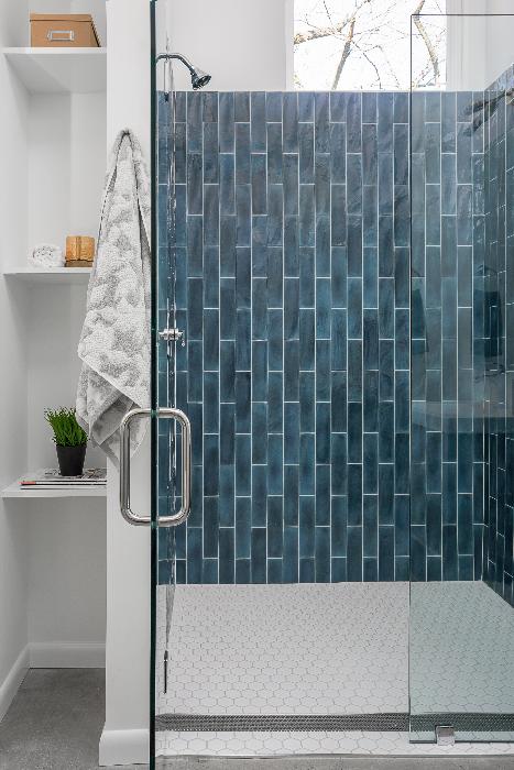 Front view of Perforated Adjustable Delmar Linear Drain in a commercial space with white oak wood flooring. The stainless-steel channel features a precision perforated grate, adjustable frame, and integrated flange for seamless installation and efficient water drainage in luxury interior designs.