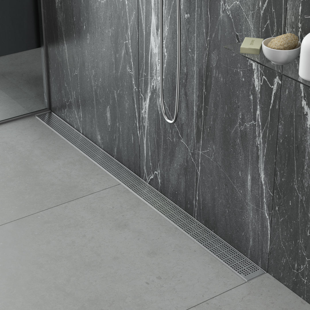 Modern spa-style bathroom scene featuring the QM Drain Kai Linear Drain—sleek stainless-steel channel set into large-format porcelain tiles, with integrated waterproof flange beneath the tile edges, minimalist grate design, and rapid high-flow drainage for a seamless luxury shower aesthetic.