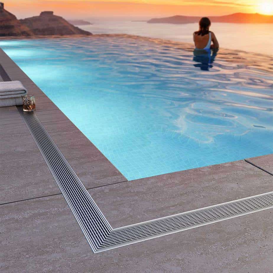 Modern outdoor terrace scene featuring the QM Drain Wedgewire Linear Drain—stainless-steel channel drain installed along stone pavers, showcasing corrosion-resistant wedge-wire grate, seamless integration, and efficient surface water evacuation for upscale landscape designs.