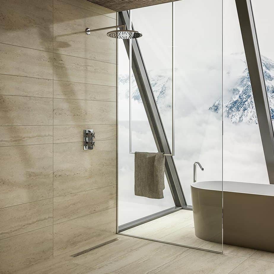 Modern spa-inspired bathroom scene featuring the QM Drain Supreme Linear Drain—sleek stainless-steel channel set into a tiled shower threshold, accented by soft lighting, lush greenery, and natural stone textures to emphasize luxury, seamless integration, and efficient water evacuation.