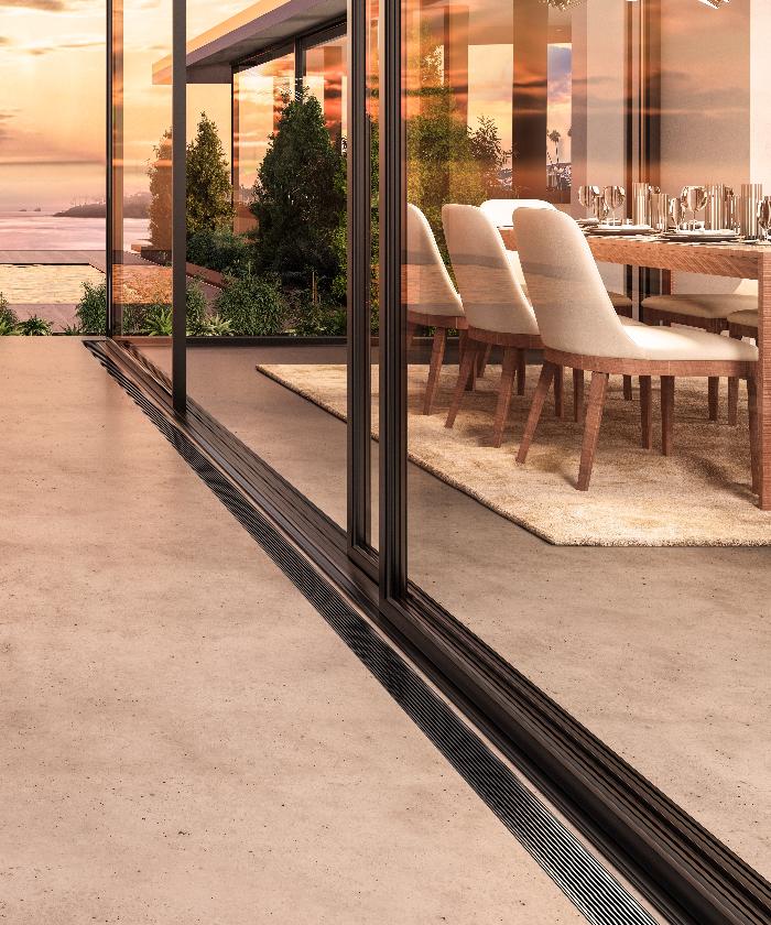 Modern outdoor terrace scene featuring the Wedgewire Delmar Adjustable Linear Drain in Black finish—stainless-steel adjustable-length channel installed along stone pavers, showcasing corrosion-resistant wedge-wire grate, integrated flange edge, and efficient surface water evacuation for upscale exterior spaces.