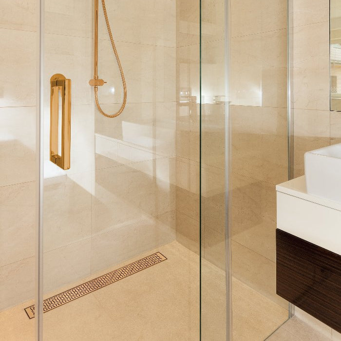 QM Drain Lotus Linear Drain in Bronze finish, featuring a sleek stainless-steel channel with a perforated grate design. This drain offers efficient water drainage, seamless tile integration, and a luxurious modern aesthetic for high-end shower and bathroom installations.