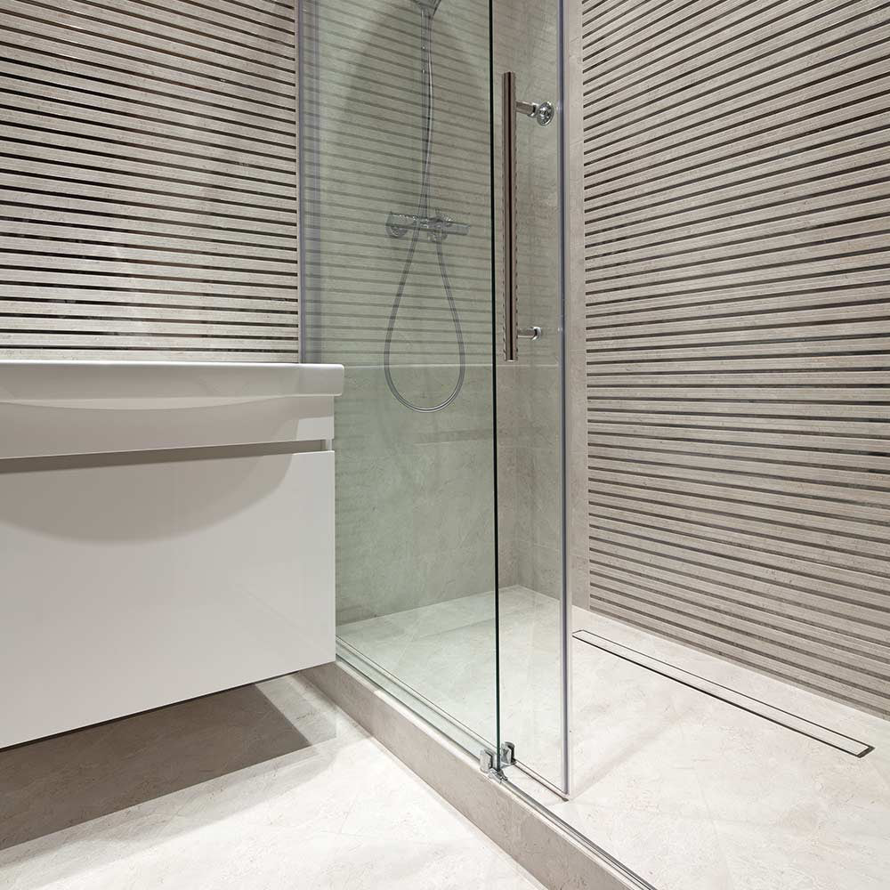 QM Drain Mist Tile-In Delmar Standard Length Plain Edge Linear Drain, featuring a sleek stainless-steel channel with a smooth, plain edge design and fine 'mist' perforated grate. This image highlights the drain’s seamless tile integration and efficient water drainage for modern luxury shower installations.