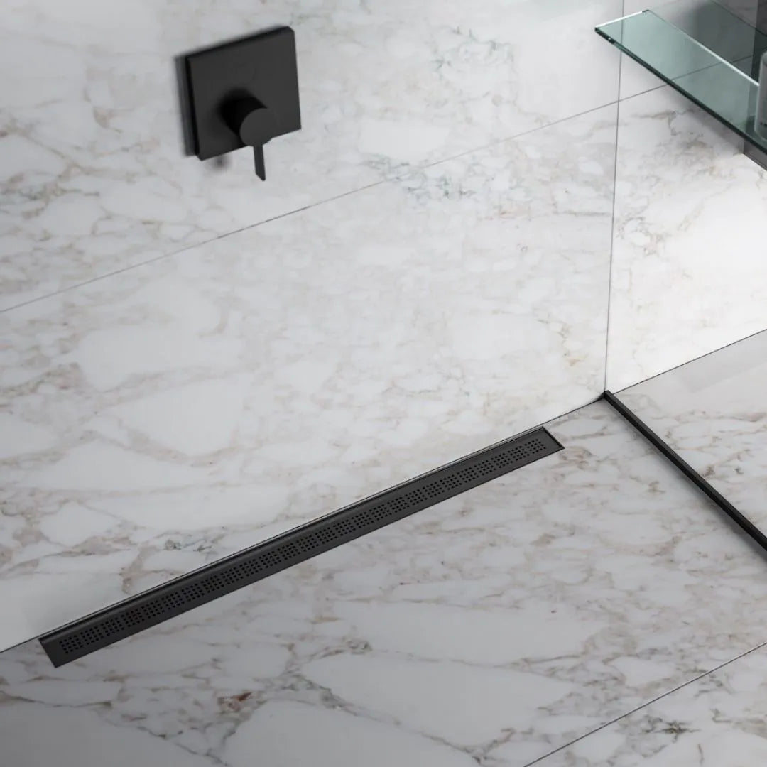 QM Drain Ria Linear Drain installed in Gold, Black, and Polished finishes, showcasing sleek stainless-steel channels with a modern perforated grate design. This drain provides efficient water drainage and seamless integration into luxury shower floors, offering a sophisticated, minimalist aesthetic.
