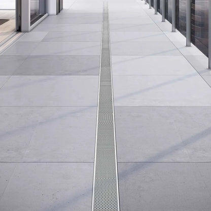 Modern outdoor setting showcasing the Perforated Outdoor Linear Drain—heavy-duty stainless-steel channel with precision perforated grate, integrated flange beneath stone pavers, and high-capacity drainage for efficient water management in exterior landscapes.