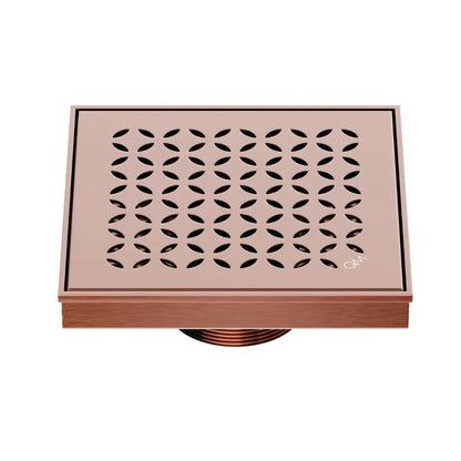 QM Drain Delmar Lotus Square Drain 5 3/4-inch in Bronze finish, featuring a sleek stainless-steel channel with an elegant floral-pattern grate. This drain offers efficient water drainage, seamless tile integration, and an elegant aesthetic, ideal for luxury shower and bathroom floor installations.