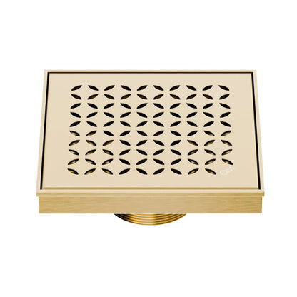 QM Drain Delmar Lotus Square Drain 5 3/4-inch in Gold finish, featuring a sleek stainless-steel channel with an elegant floral-pattern grate. This drain provides efficient water drainage, seamless tile integration, and a luxurious aesthetic, ideal for high-end shower and bathroom floor installations.