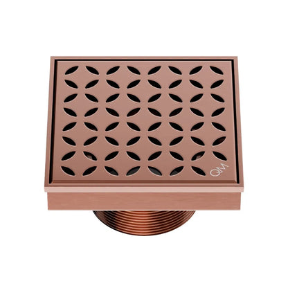 QM Drain Delmar Lotus Square Drain 4x4-inch in Bronze finish, featuring a sleek stainless-steel channel with an elegant floral-pattern grate. This drain offers efficient water drainage, seamless tile integration, and an elegant aesthetic, ideal for luxury shower and bathroom floor installations.