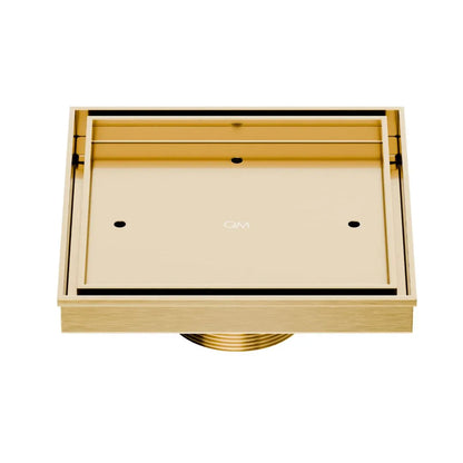 QM Drain Delmar Mist Tile-In Square Shower Drain 5 3/4-inch in Gold finish, featuring a sleek stainless-steel channel with a 'mist' perforated grate design. This drain provides seamless tile integration, efficient water drainage, and a luxurious aesthetic for high-end shower and bathroom floor installations.