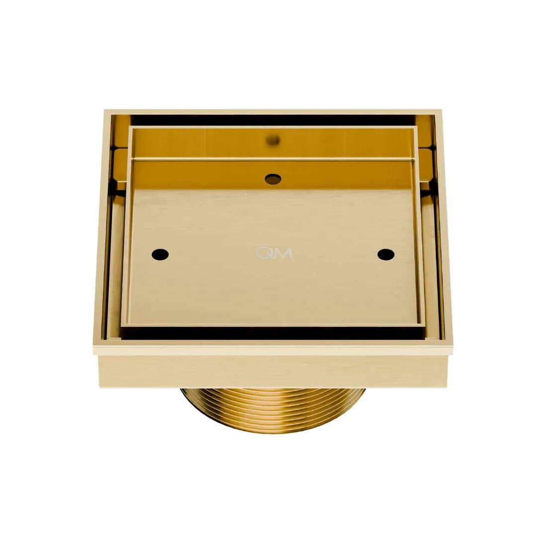 QM Drain Delmar Mist Tile-In Square Shower Drain 4x4-inch in Gold finish, featuring a sleek stainless-steel channel with a 'mist' perforated grate design. This drain allows seamless tile integration, offering efficient water drainage and a luxurious aesthetic for high-end shower and bathroom floor installations.