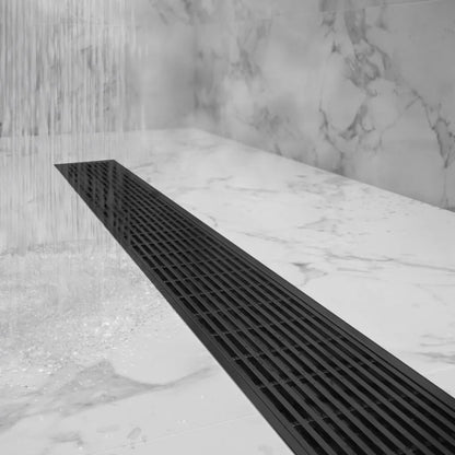 Top-down shot of bathroom floor featuring Delmar flange-edge drain in polished finish, emphasizing the flush grate, perimeter flange, and high-flow wedge-wire design.