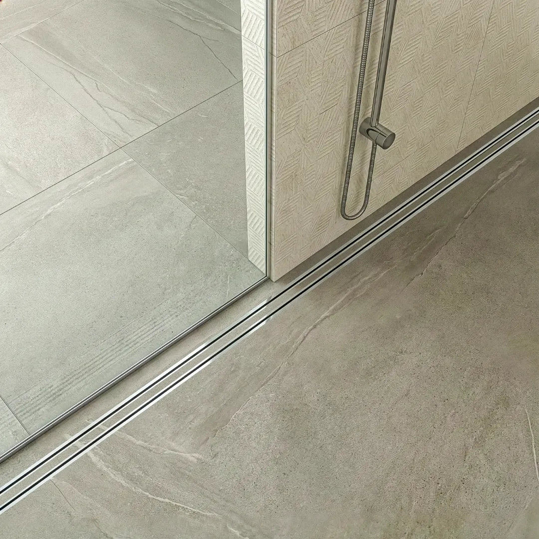 Detail of the Mist Couture Lagos tile-in grate by QM Drain, showcasing how the drain virtually disappears into the shower floor. This marine-grade 316 stainless steel solution is ideal for high-end residential projects seeking a sophisticated and unobstructed finish.