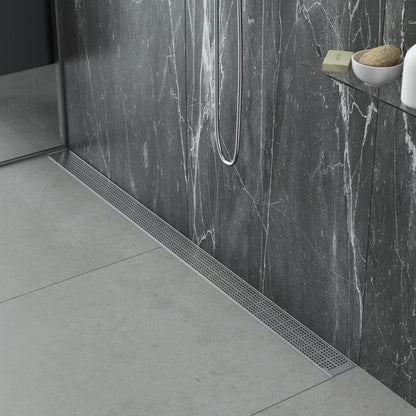 Modern spa-style bathroom scene featuring the QM Drain Kai Linear Drain—sleek stainless-steel channel set into large-format porcelain tiles, with integrated waterproof flange beneath the tile edges, minimalist grate design, and rapid high-flow drainage for a seamless luxury shower aesthetic.