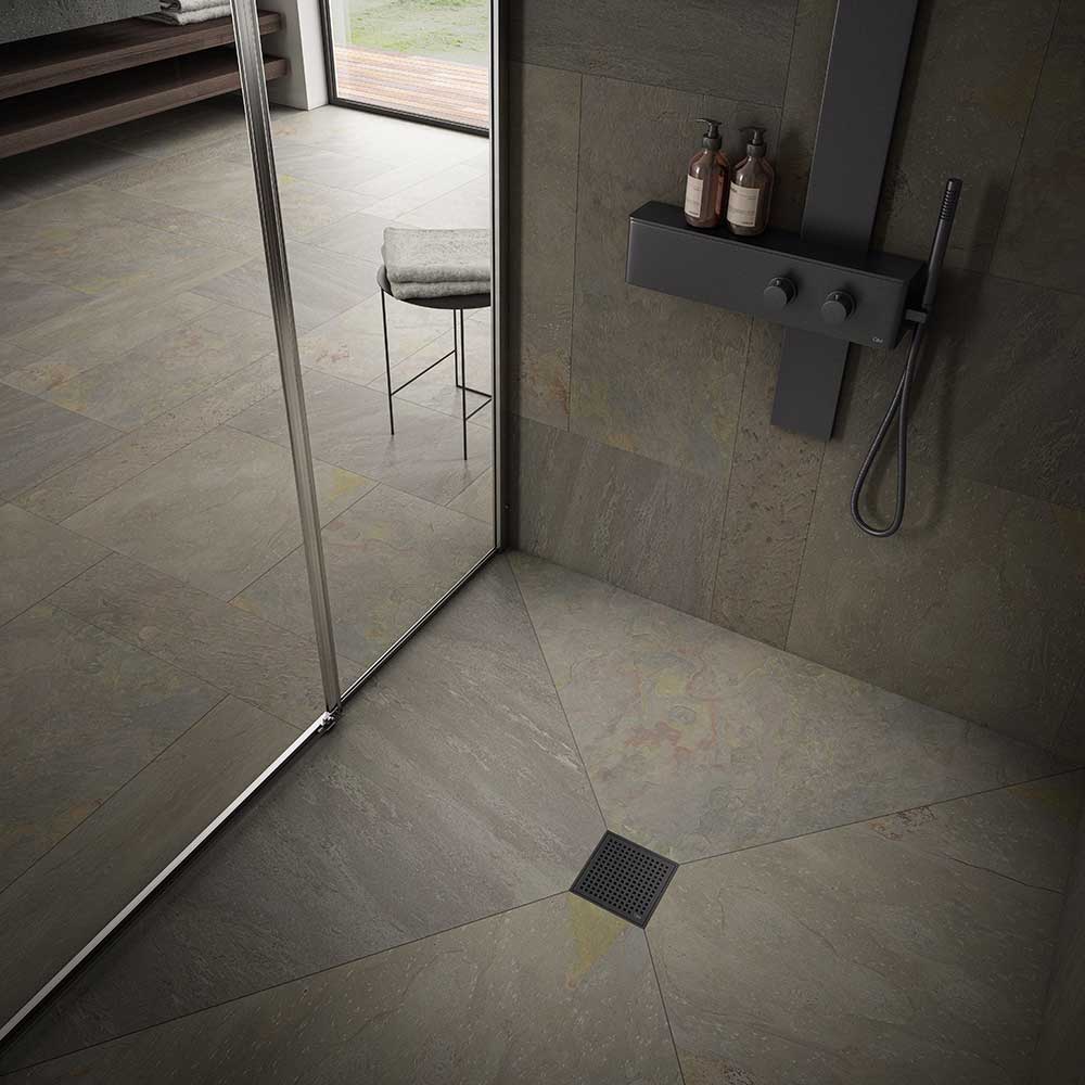 Modern shower floor showcasing the QM Drain Mira Square Drain in Black finish—4″×4″ stainless-steel tile-insert grate with subtle curved slots, integrated waterproof flange, and efficient high-flow drainage for sleek, contemporary bathroom designs.