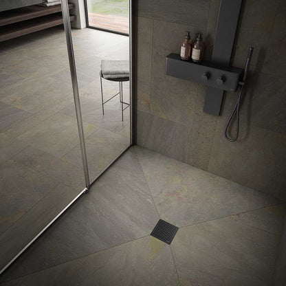 Modern shower floor showcasing the QM Drain Mira Square Drain in Black finish—4″×4″ stainless-steel tile-insert grate with subtle curved slots, integrated waterproof flange, and efficient high-flow drainage for sleek, contemporary bathroom designs.