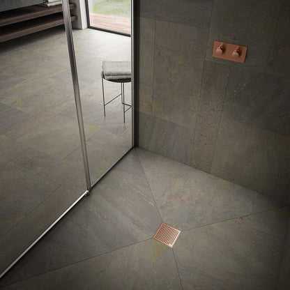 Modern shower floor showcasing the QM Drain Mira Square Drain in Bronze finish—4″×4″ stainless-steel tile-insert grate with subtle curved slots, integrated waterproof flange, and efficient high-flow drainage for sleek, contemporary bathroom designs.