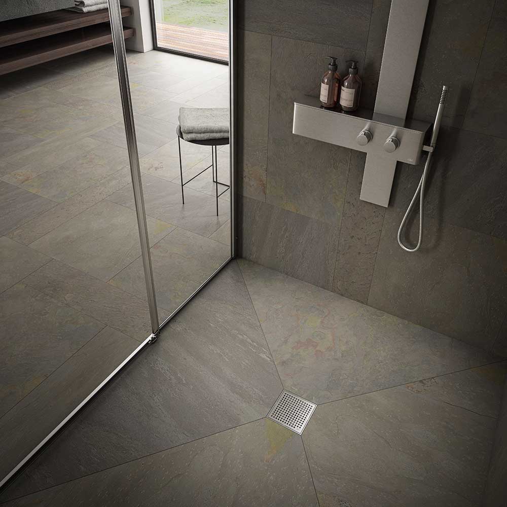 Modern shower floor showcasing the QM Drain Mira Square Drain in Satin finish—4″×4″ stainless-steel tile-insert grate with subtle curved slots, integrated waterproof flange, and efficient high-flow drainage for sleek, contemporary bathroom designs.