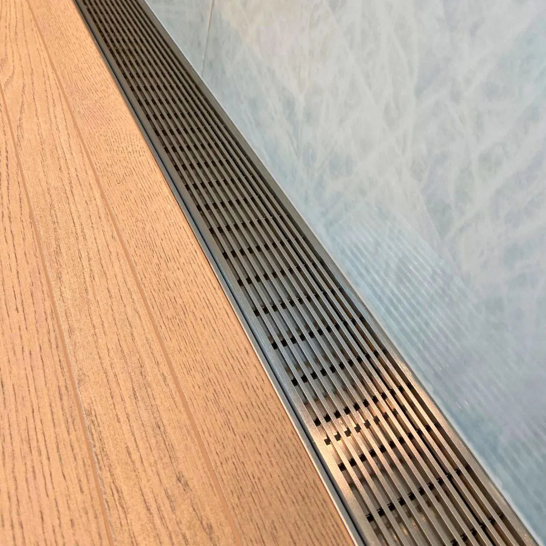 Modern shower floor showcasing the QM Drain Adjustable Wedgewire Linear Drain—stainless-steel channel with corrosion-resistant wedge-wire grate and adjustable frame, installed flush within large-format tiles for seamless integration and efficient high-flow water evacuation.