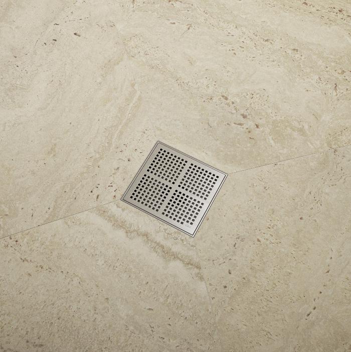 QM Drain Delmar Kai Square Drain installed in a modern bathroom setting, featuring a stainless-steel grate with fine square perforations. The image highlights seamless tile integration and efficient water drainage, offering a sleek, minimalist aesthetic perfect for luxury shower and bathroom installations.